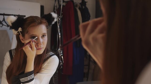 Young cosplayer applying eye makeup in front of a mirror