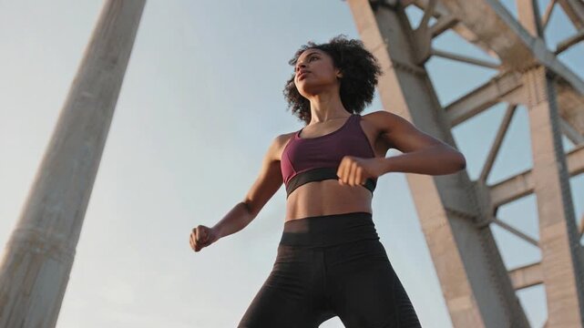 Young African American woman in athletic attire, exuding confidence and determination from a low angle perspective, cinematic scene