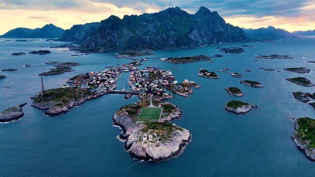 Nestled among rugged mountains, Henningsvaer showcases vibrant houses and a scenic harbor, surrounded by crystal-clear waters. A breathtaking view capturing Norways natural splendor at sunset.