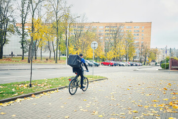 Food delivery. Pizza delivery courier ride on bicycle in cloudy autumn day. Food delivery man delivering pizza from restaurant in autumn season. Pizza delivery service.