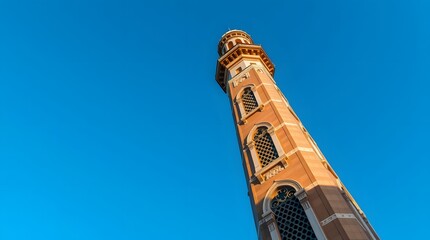 Majestic Islamic minaret tower viewed from a low angle, reaching up towards a vibrant clear blue sky
