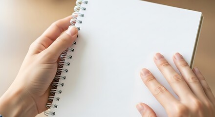 Hands holding open spiral notebook with bright, clean blank page