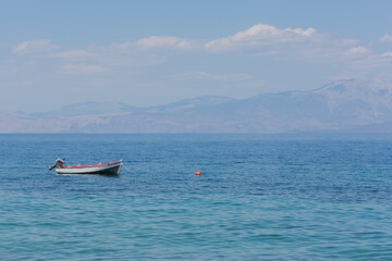 Tiny boat floating in blue, calm mediterranean sea at gulf of Corinth, Peloponnes, Greece