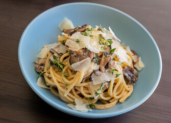 creamy pasta dish topped with savory mushroom sauce, grated parmesan, and fresh thyme, served in a blue bowl
