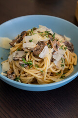 creamy pasta dish topped with savory mushroom sauce, grated parmesan, and fresh thyme, served in a blue bowl
