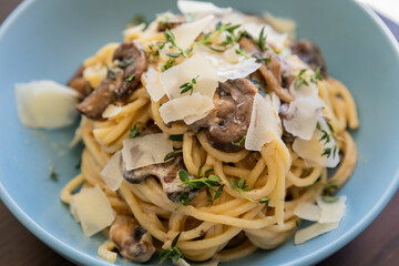 creamy pasta dish topped with savory mushroom sauce, grated parmesan, and fresh thyme, served in a blue bowl