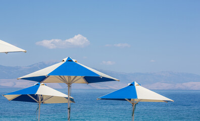 Sun shades (beach umbrellas) with blue, calm mediterranean sea at gulf of Corinth, Peloponnes, Greece