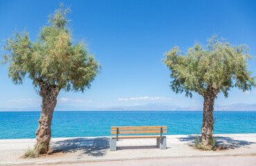 Place to relax: Bank, trees and blue, calm mediterranean sea at the promenade of Xylocastro, gulf of Corinth, Peloponnes, Greece