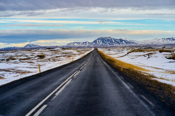Wanderful landscape view with snow peak mountain and empty road for road trip in Iceland and blue sky with cloud.