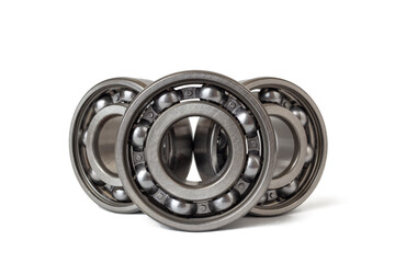 View of three steel ball bearings arranged in a row. The bearings are open, revealing the polished metal balls held within their circular races.