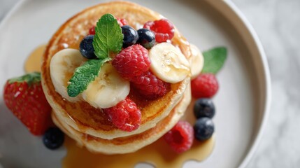 vibrant top view of oat flour pancakes stacked with maple syrup, banana slices, and berries