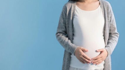 Pregnant woman holding her belly against a blue background