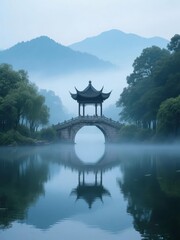 Traditional Chinese pavilion bridge over calm lake with mountain backdrop in misty morning