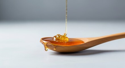 Golden honey pours onto a wooden spoon creating a sweet viscous flow.