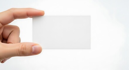 Fototapeta premium Close-up of a hand presenting a blank white business card on a white background, perfect for custom text or logo integration.