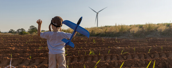 Boy Playing on field on wind farm. Happy Boy playing at the Wind turbines generating electricity. Family time together.