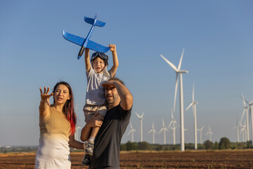 Family with son walking on field on wind farm. Happy Family and son playing at the Wind turbines generating electricity. Family time together.