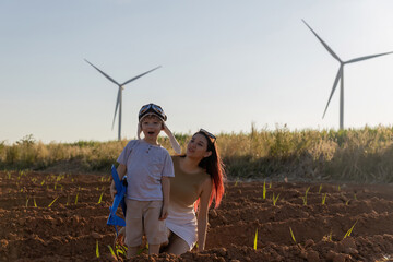 Family with son walking on field on wind farm. Happy Family and son playing at the Wind turbines generating electricity. Family time together.