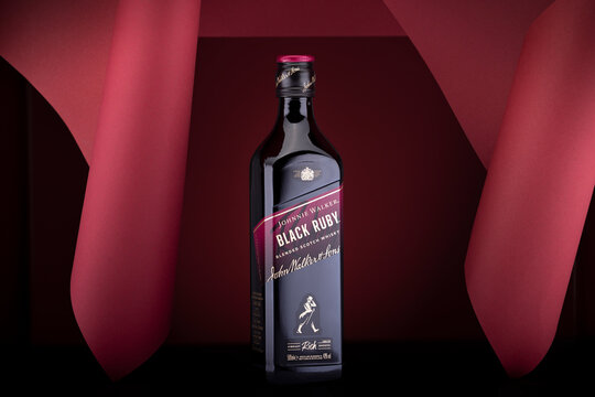 Johnnie Walker Black Ruby blended Scotch whisky bottle. Special edition presented in an elegant red background composition, symbolizing luxury and premium spirits.