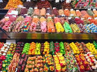 Marmalade on the store counter, colorful candies of different colors and shapes A fruit candies stand with a variety of fruits and candies. There are apples, oranges, bananas, and pears