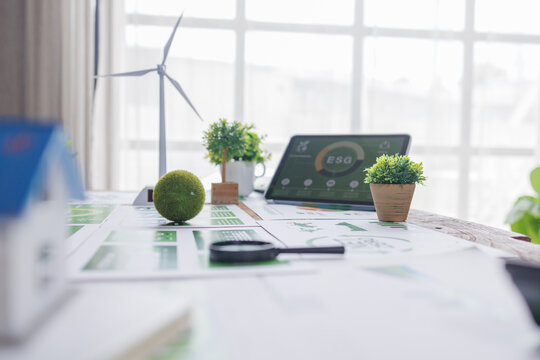 esg small green ball symbolizing earth ESG environment, social,governance recycle sign on laptop screen with carbon free chart board in office
