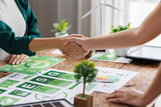 Close up of business people shaking hands over ESG strategic commitment workshop, SDGs report, global warming, green finance investment eco friendly and net zero waste in boardroom training building.
