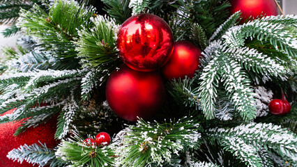 Decorated Christmas tree with red baubles ornaments and artificial snow, background
