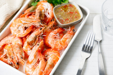Grilled shrimps with spicy sauce in a white tray.