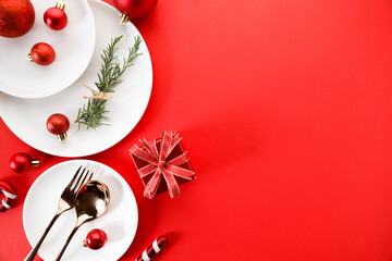 White dishes with Christmas ornaments on red background.