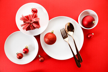 White dishes with Christmas ornaments on red background.