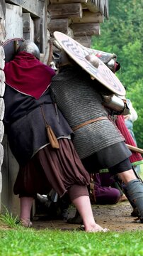 Medieval knights storm the wooden gate in the castle. Reconstruction of knightly battles