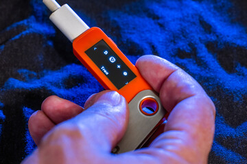 Hand holding orange hardware wallet with Tron symbol