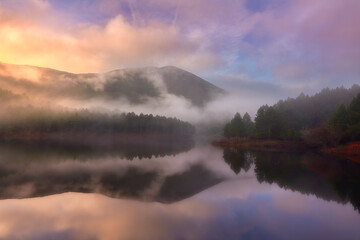 Obraz premium Misty Lake with Sunrise Reflections in Mountain Landscape