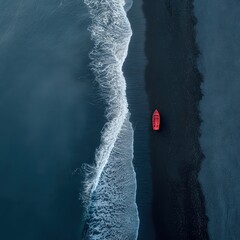 Aerial view of a single red boat near the shore with contrasting blue ocean waves and black sand beach, creating a striking natural landscape