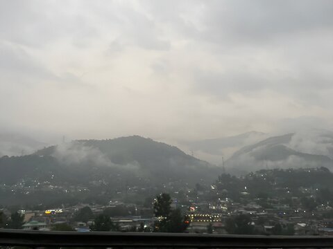 Misty morning embraces the quiet valley town, where clouds descend upon rolling hills, weaving a veil of mystery. Shadows of mountains fade softly into the horizon, painting a timeless portrait of ser