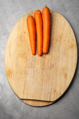 Fresh carrots on wooden cutting board in kitchen