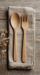 Wooden spoon and fork on a napkin, on a light-colored wooden table, with dried flowers