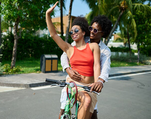 Portrait of a young black couple having fun riding a bike during a summer vacation