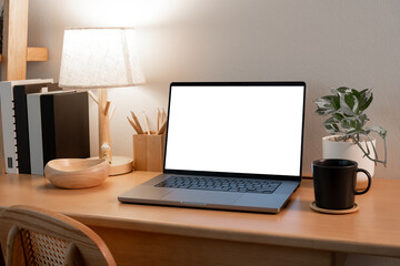 A modern laptop with a blank screen is positioned on a wooden desk. The inviting light creates a cozy and professional home office setting, ideal for showcasing designs, or use as a product mockup.
