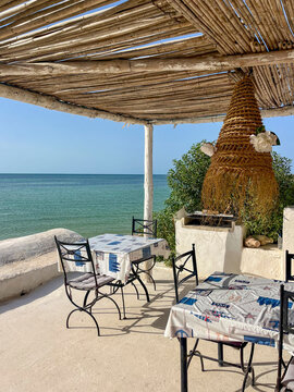 Sun loungers are arranged on a sandy beach in Djerba, Tunisia. Clear blue skies and turquoise water create a perfect paradise for relaxation.