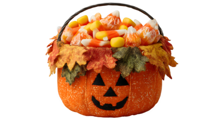 Jack-o-lantern bucket decorated with autumn leaves, filled with candy corn, isolated on white background