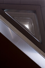 Fototapeta premium An abstract view looking up the stacked balconies of a modern building in the fog. The angular and repetitive pattern creates a feeling of depth and a strong contrast with the bright white light.