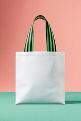 Blank white tote bag with lime green and black striped handles against a pink and teal background