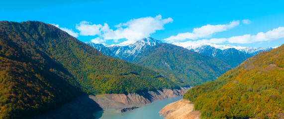Breath taking view of cloudy with blue sky and blue river mountain in Autumn scene with snow at Mestia Georgia, autumn forest