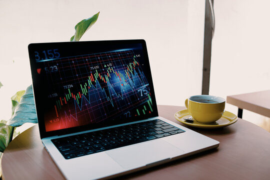 analyzing stock market data on a laptop with financial trading charts and a cup of coffee at home.
