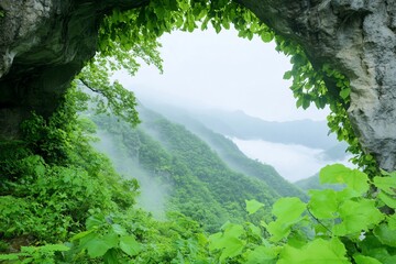 Lush Green Mountains Framed by a Natural Rock Archway on a Misty Day