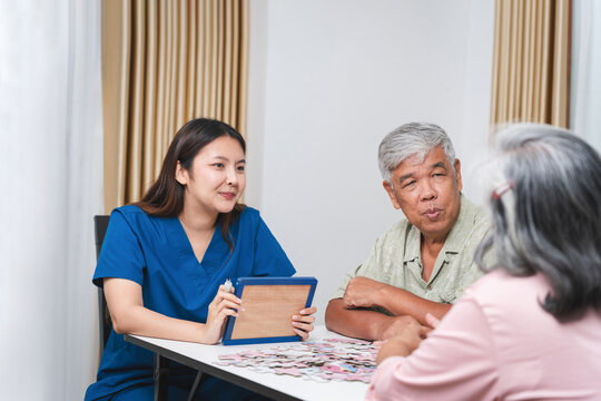 Caregiver Assisted Senior Couple with Puzzle at Home, Nurse Helps Elderly Patients with Cognitive Games, Young Nurse and Senior Couple Enjoy Leisure Time Together