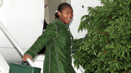 A close-up of a young African woman holding a suitcase while boarding a plane, soft daylight highlighting her confident and excited demeanor.