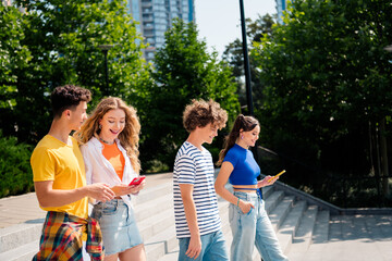 Group of young friends enjoying a summer day outdoors, walking together and staying connected with their smartphones