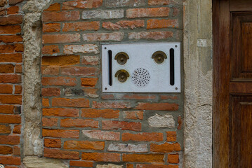 A weathered Venetian brick wall frames an old intercom system, its metal worn by time and the elements. Three brass bells look like curious eyes. Venice hides charming details in plain sight.
